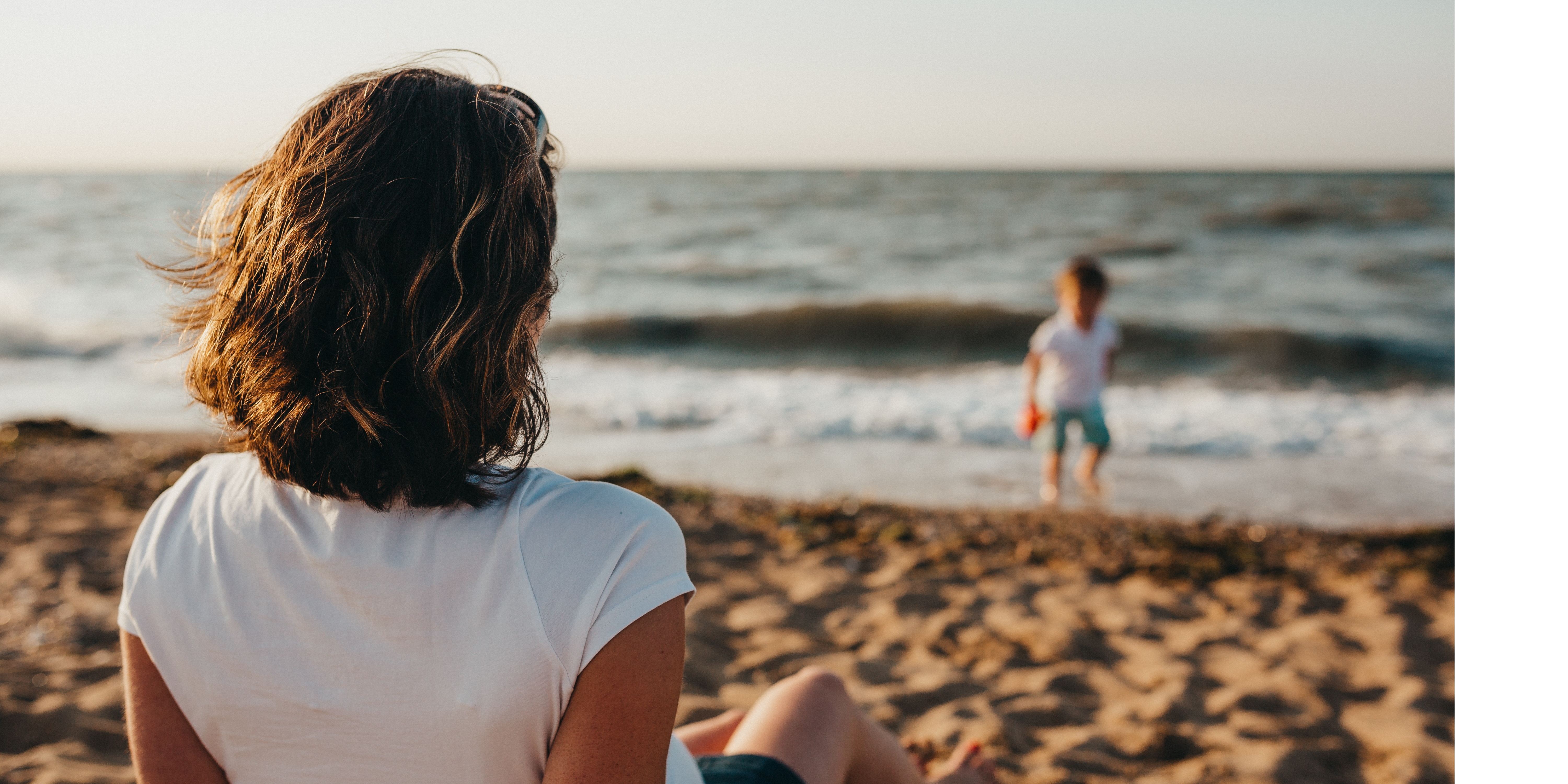 Single Mum Watching Child Play On The Beach