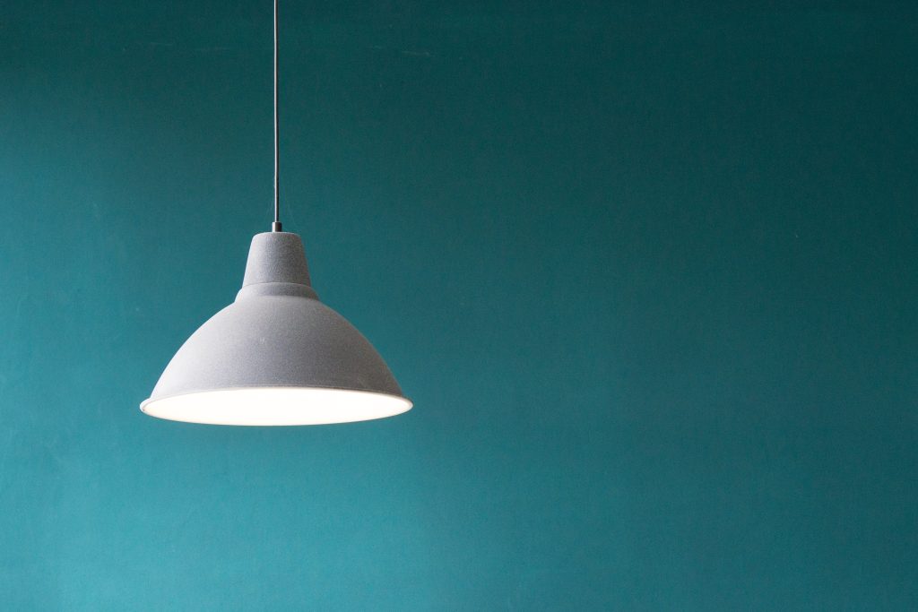 Hanging grey pendant light against a teal wall