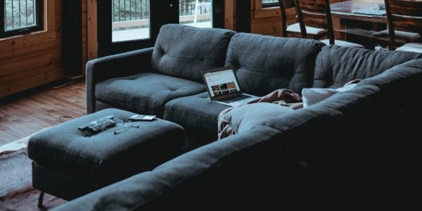 L-shaped dark couch, with a laptop on top.  