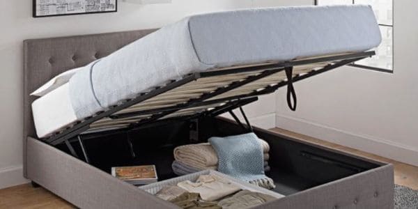 An open storage bed with items inside, including clothes and blankets