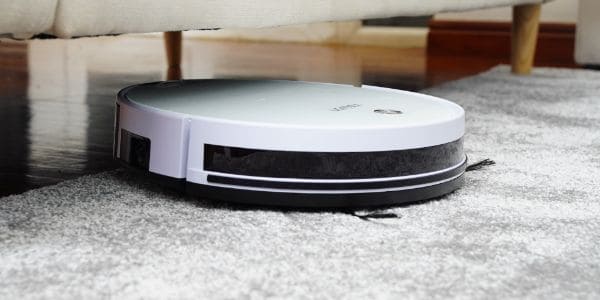 A white robot vacuum under under a sofa 