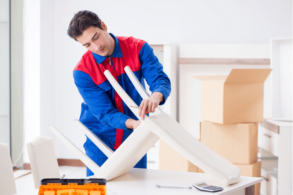 MIddle aged man trying to disassemble a white chair.