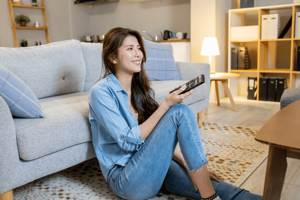 Middle aged woman seated on the floor with a TV control remote 